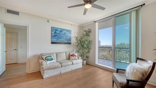 living room featuring visible vents, baseboards, light wood-style floors, and ornamental molding