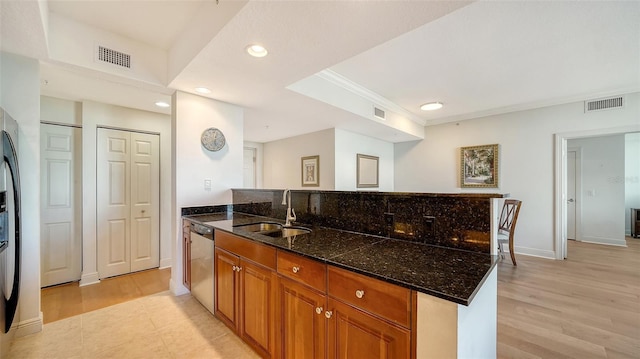 kitchen with sink, dishwasher, ornamental molding, dark stone counters, and light wood-type flooring