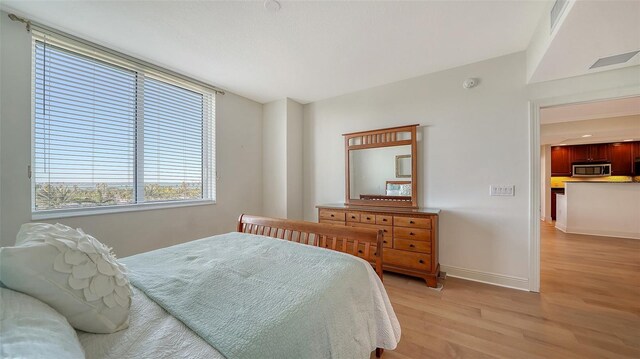 bedroom with visible vents, light wood-style flooring, and baseboards