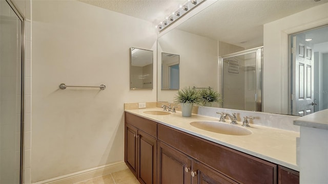 bathroom with a shower with door, vanity, tile patterned floors, and a textured ceiling