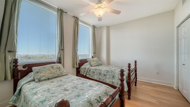 bedroom with a closet, baseboards, a ceiling fan, and light wood finished floors