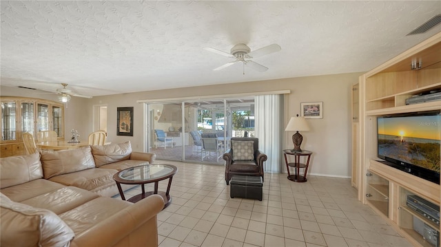 living room with ceiling fan, light tile patterned floors, and a textured ceiling