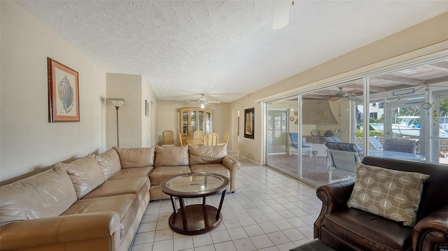 living room with a textured ceiling, ceiling fan, and light tile patterned flooring