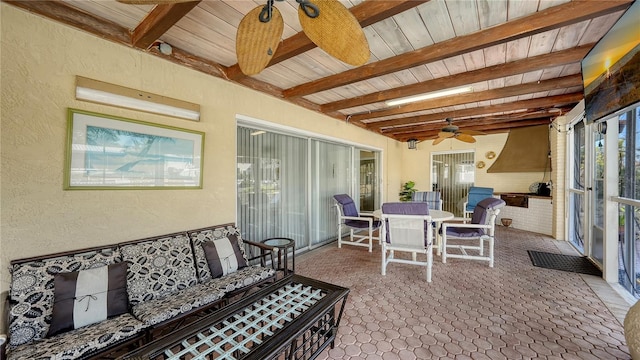 sunroom / solarium with ceiling fan, beam ceiling, and a wealth of natural light