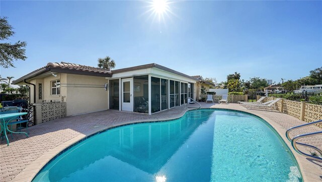 view of pool with a sunroom and a patio area