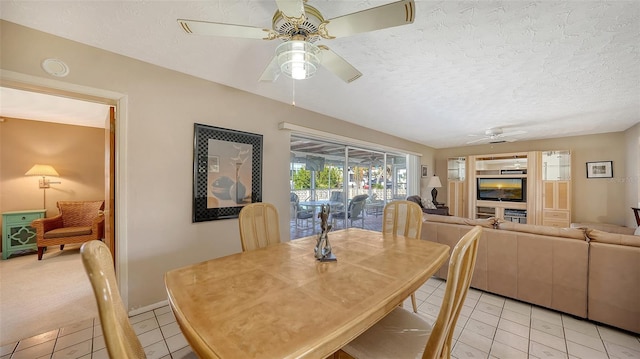 tiled dining area with ceiling fan and a textured ceiling