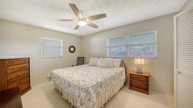 carpeted bedroom featuring multiple windows and ceiling fan