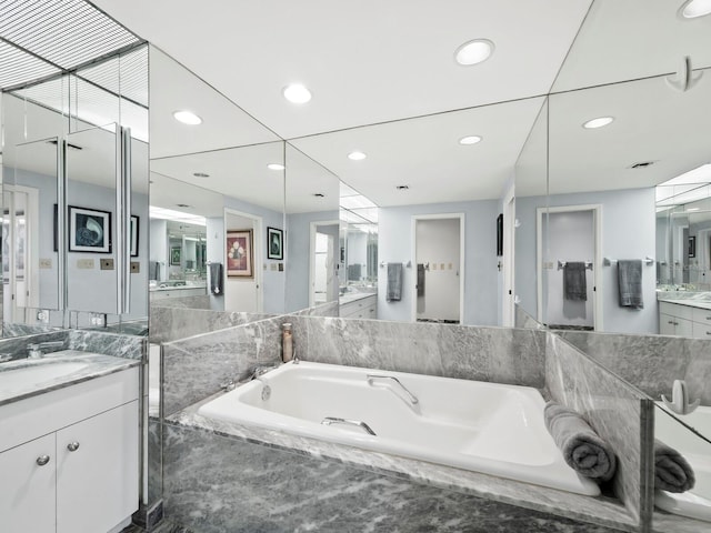 bathroom with vanity and tiled bath