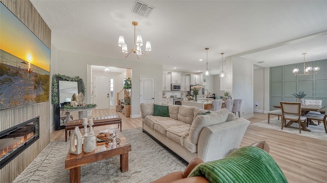 living room with a chandelier, light hardwood / wood-style floors, and sink