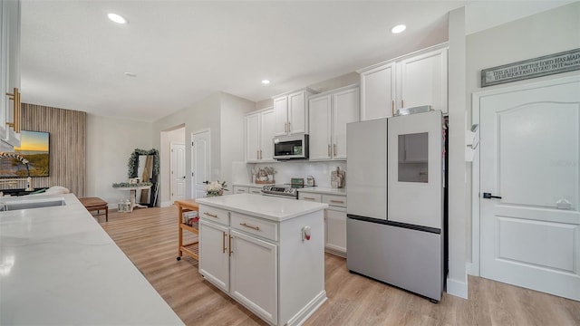 kitchen featuring white cabinets, a center island, appliances with stainless steel finishes, and light hardwood / wood-style flooring