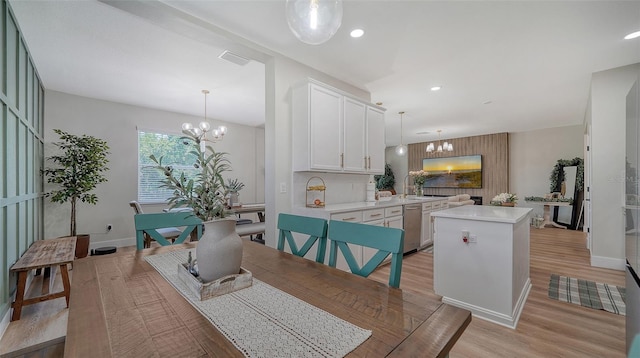 dining space with sink, a chandelier, and light wood-type flooring