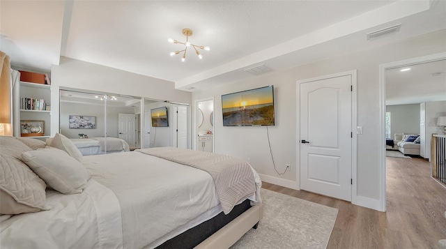 bedroom featuring an inviting chandelier and light hardwood / wood-style flooring