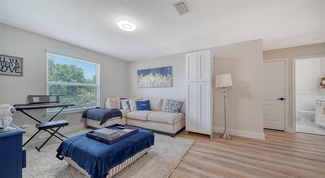 living room with a textured ceiling and light wood-type flooring