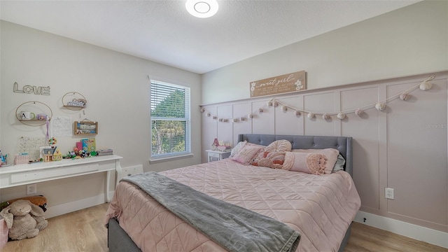 bedroom with a textured ceiling, light hardwood / wood-style flooring, and vaulted ceiling