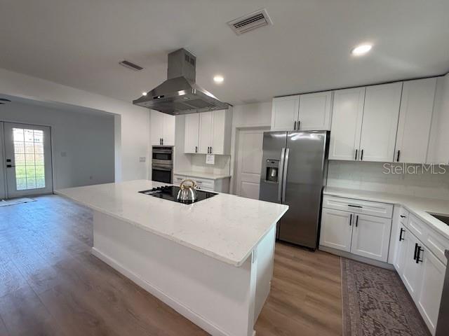 kitchen with white cabinetry, stainless steel fridge with ice dispenser, and wall chimney exhaust hood