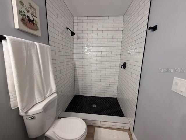 bathroom featuring toilet and a tile shower