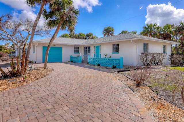 single story home featuring a garage, decorative driveway, and stucco siding