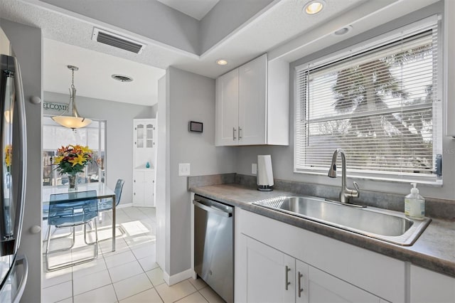 kitchen with stainless steel dishwasher, sink, white cabinetry, hanging light fixtures, and light tile patterned flooring