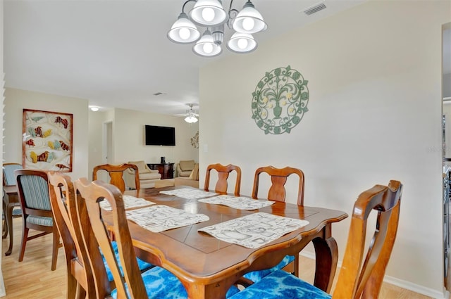 dining space with ceiling fan with notable chandelier and light wood-type flooring