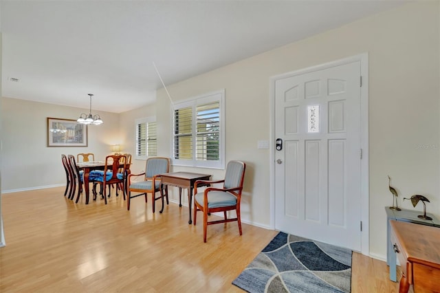 foyer entrance with light hardwood / wood-style flooring and an inviting chandelier