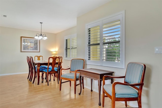 dining area with light hardwood / wood-style flooring and a notable chandelier