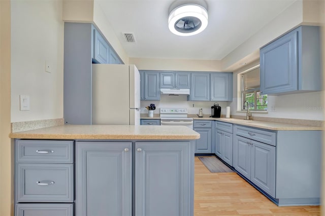 kitchen with kitchen peninsula, white appliances, light hardwood / wood-style floors, and sink