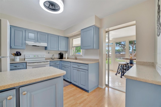 kitchen with electric range, white refrigerator, light wood-type flooring, and sink