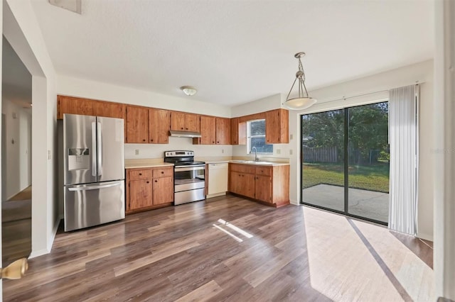 kitchen featuring decorative light fixtures, dark hardwood / wood-style floors, sink, and stainless steel appliances