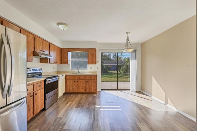 kitchen featuring appliances with stainless steel finishes, dark hardwood / wood-style flooring, a textured ceiling, sink, and hanging light fixtures