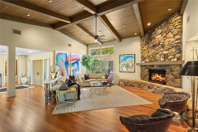 living room with wood ceiling, ceiling fan, hardwood / wood-style flooring, high vaulted ceiling, and a stone fireplace