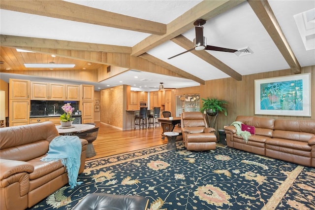 living room with hardwood / wood-style floors, sink, ceiling fan, and vaulted ceiling with skylight