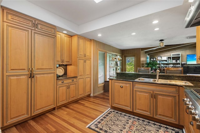 kitchen featuring dark stone counters, stainless steel range, ceiling fan, light hardwood / wood-style floors, and lofted ceiling