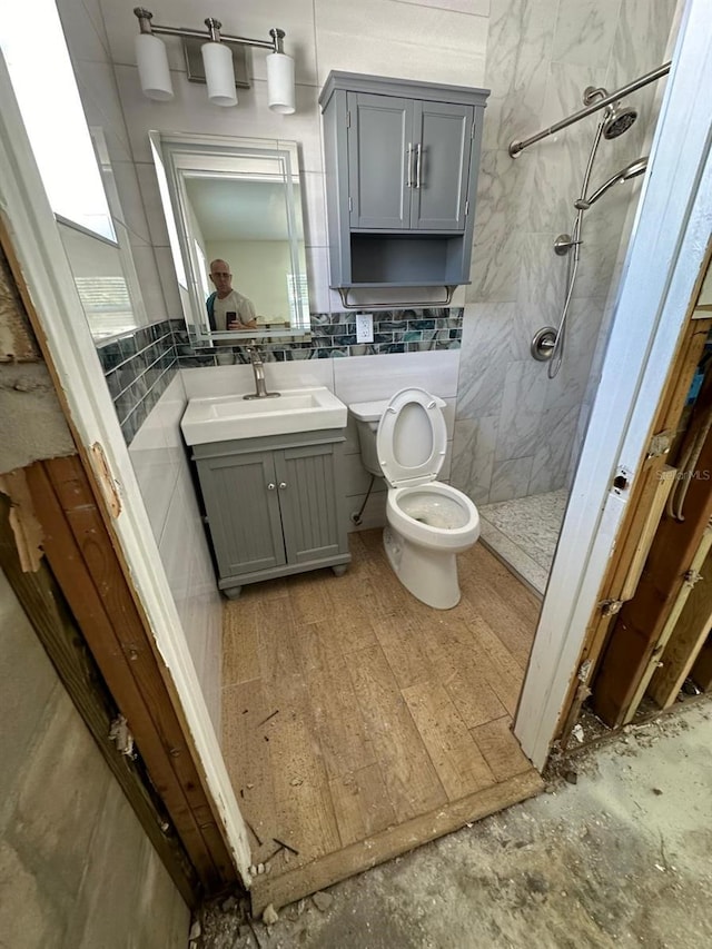 bathroom with a tile shower, vanity, and toilet