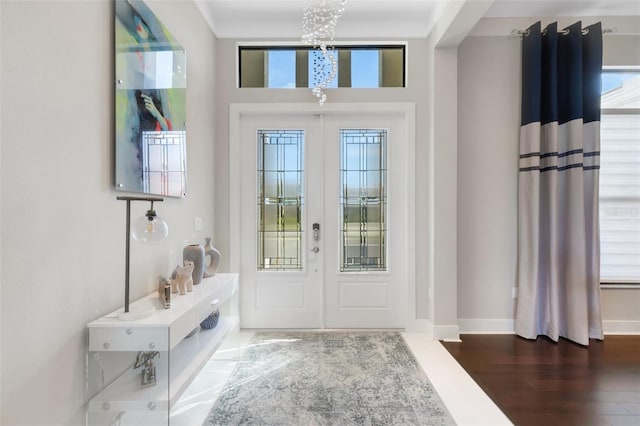 foyer entrance featuring hardwood / wood-style flooring, a notable chandelier, and french doors