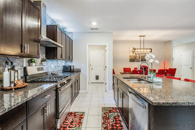 kitchen with sink, an island with sink, appliances with stainless steel finishes, tasteful backsplash, and light tile patterned flooring