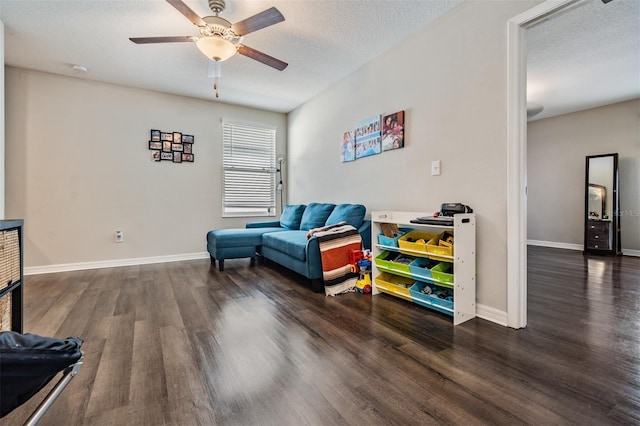 living area with ceiling fan, dark wood-type flooring, and a textured ceiling