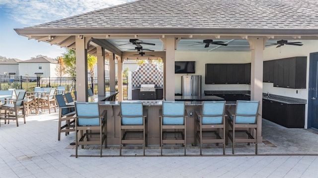 view of patio with exterior bar, grilling area, and ceiling fan