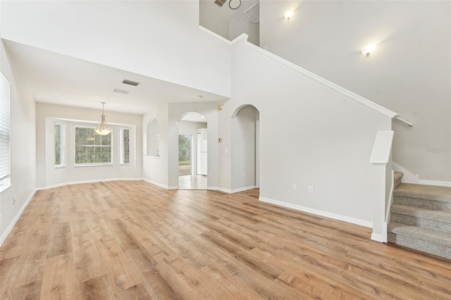 unfurnished living room featuring a towering ceiling and light wood-type flooring