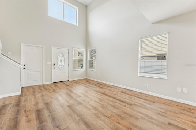 foyer featuring a towering ceiling, light hardwood / wood-style flooring, and a healthy amount of sunlight