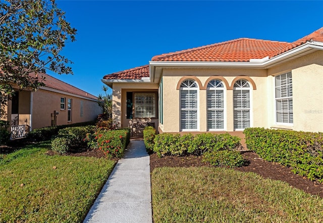 616 Misty Pond Ct, Bradenton, FL 34212 - view of exterior entry with a tile roof, stucco siding, and a lawn