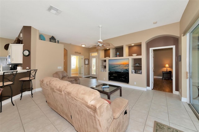 tiled living room featuring built in shelves and ceiling fan