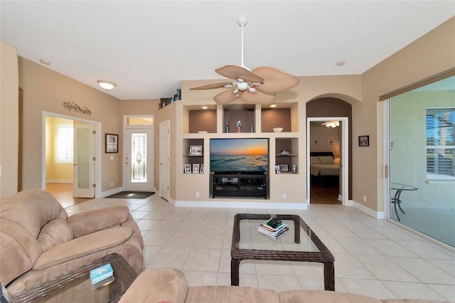 living room featuring built in shelves, light tile patterned flooring, and ceiling fan