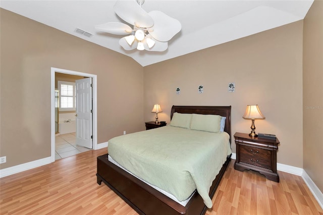 bedroom with ceiling fan, ensuite bathroom, vaulted ceiling, and light wood-type flooring