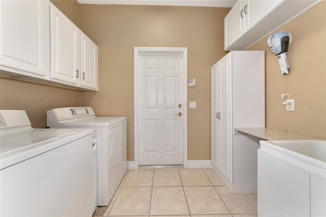 clothes washing area with separate washer and dryer, light tile patterned floors, and cabinets