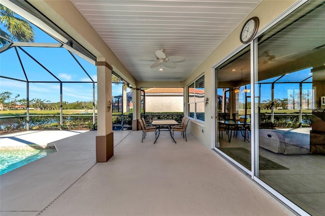 view of patio with a water view, glass enclosure, and ceiling fan