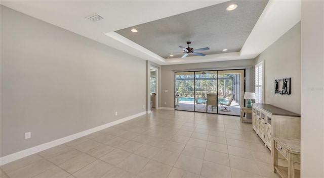 tiled spare room with a raised ceiling and ceiling fan