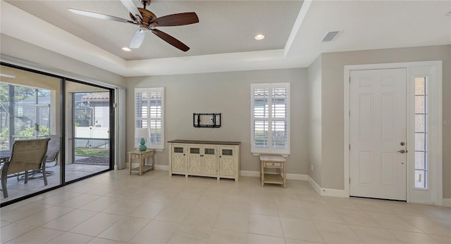 foyer entrance featuring a raised ceiling, ceiling fan, and light tile patterned flooring