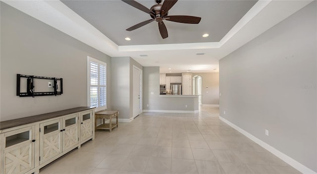 living room with a raised ceiling and ceiling fan