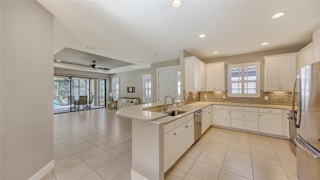 kitchen with ceiling fan, sink, kitchen peninsula, white cabinets, and appliances with stainless steel finishes