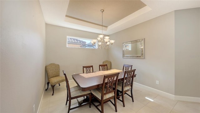 tiled dining area featuring a notable chandelier and a tray ceiling